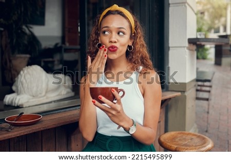 Coffee, cafe and hand of a black woman with funny face while sitting by a counter at an outdoor restaurant. Coffee shop, quirky and makeup with a playful young female enjoying a drink from a mug