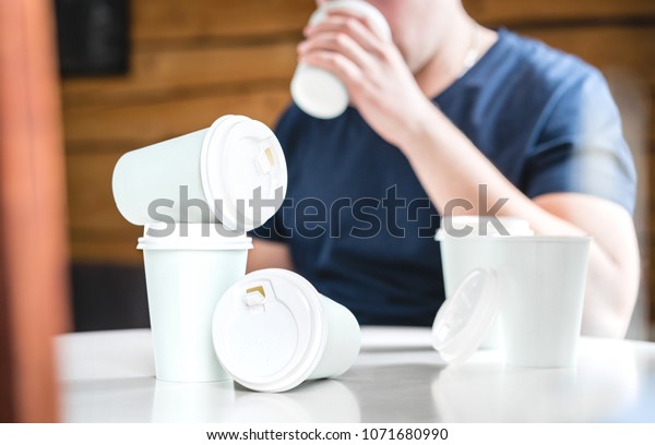 Coffee or caffeine addiction concept.\
Addicted or thirsty man drinking too much. Addict with many empty\
take away paper cups on table. Trying to stay\
awake.