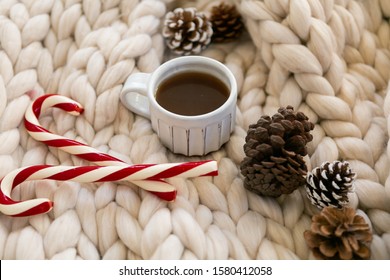 Coffee And Candy Canes On Chunky Knit Blanket Styled With Pine Cones, Cozy Christmas Photo