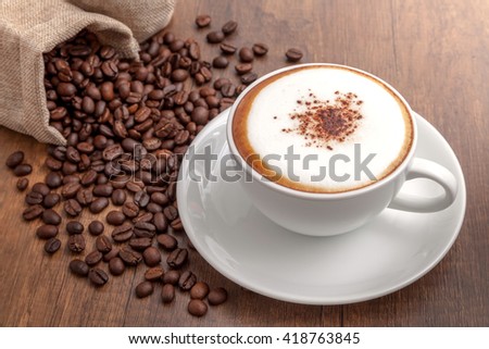 Coffee cappuccino and coffee beans on wooden background