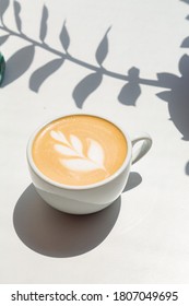 Coffee Cappuccino On White Background With Sun Light Shadows In Flowers Form 