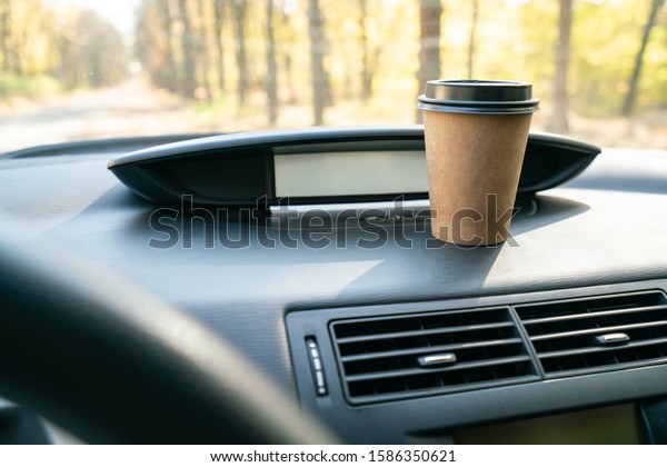 Coffee in car. Coffee\
cup on car console.