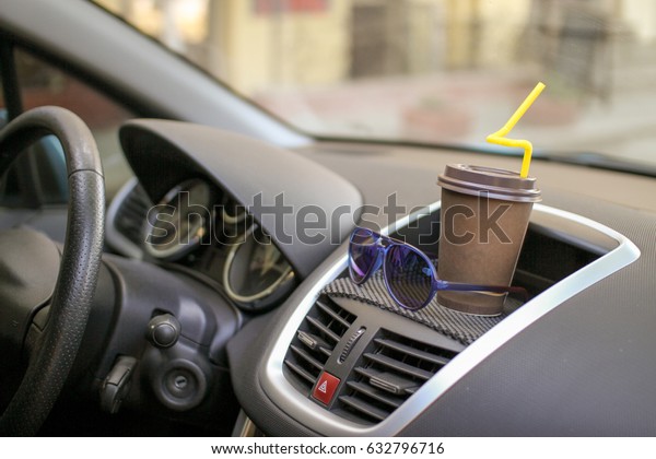 Coffee in car. Cup of coffee and sunglasses on\
the car console (panel),\
closeup