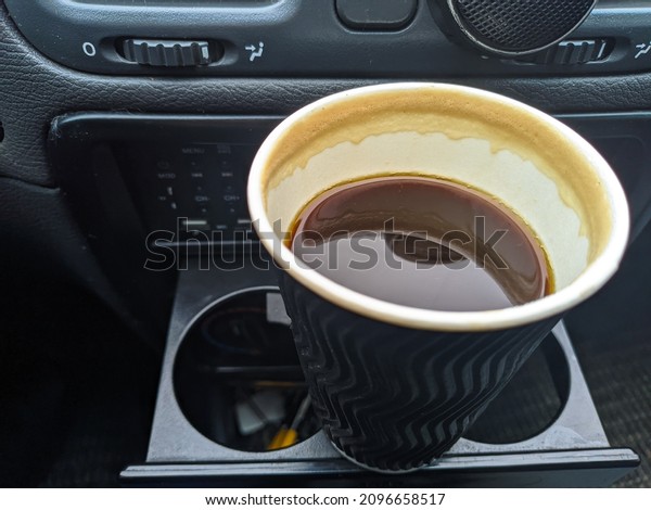 coffee in the car. Man\
holding coffee paper cup in car. coffee is a friend of traveler.\
transportation and vehicle concept - man drinking coffee while\
driving the car. 