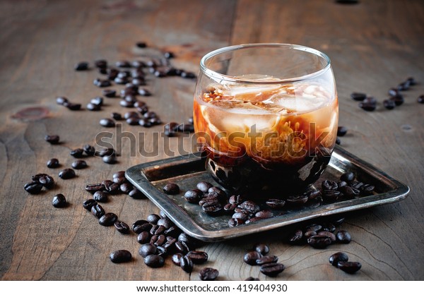 Coffee cocktail with cream, White Russian,  liquor\
in glasses with coffee beans on a wooden background, selective\
focus, toned image
