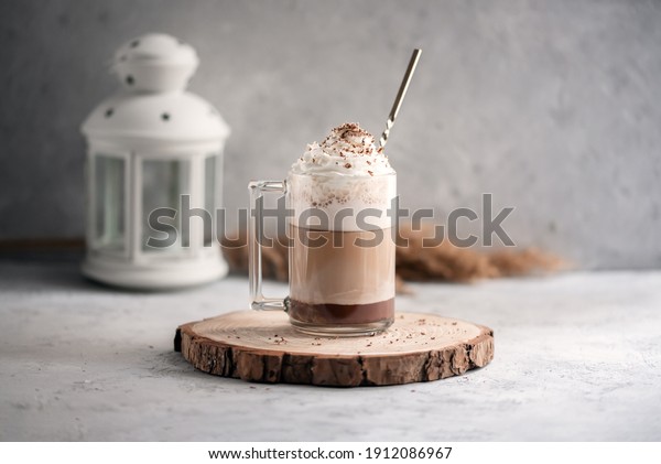Coffee cocktail mocha with whipped cream on a\
wooden tray on a stone gray background. Delicious homemade sweet\
dessert of coffee with milk and\
cocoad.