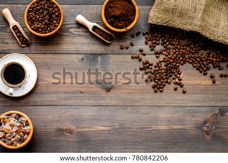 Coffee concept. Roasted beans, ground coffee, cup of espresso and sugar on dark wooden background top view copyspace
