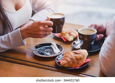 coffee and croissants in cafe, hands of couple closeup - Shutterstock ID 344431760