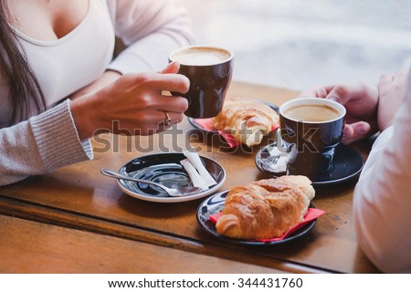coffee and croissants in cafe, hands of couple closeup