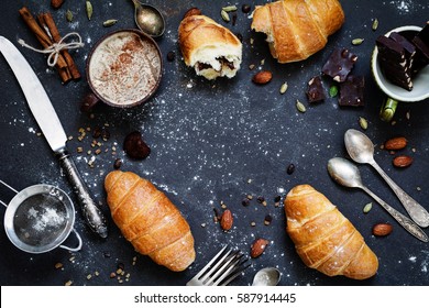 Coffee, croissants, chocolate, spices, nuts and vintage cutlery. Flat lay composition of sweet breakfast food on dark stone background with copy space for text. Table top view - Powered by Shutterstock