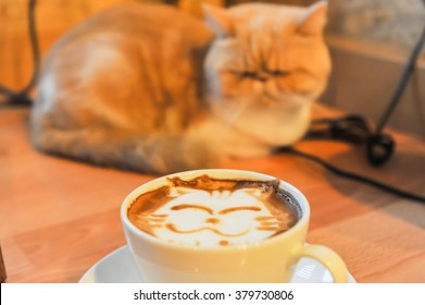 Coffee cup with artistic cream cat face decoration, blured cat backgroud