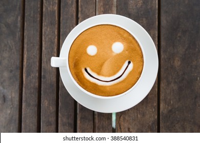 Coffee Cup With Artistic Cream Smile Face Decoration On Wooden Table Background