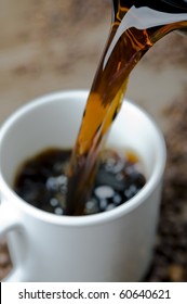 Coffee cup being filled, surrounded by coffee beans