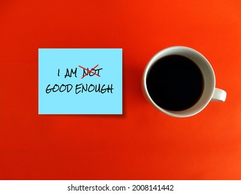 Coffee cup, blue note on orange background written I AM NOT GOOD ENOUGH with red cross on NOT, an aspiration motivation affirmation or positive self talk to boost self esteem ,encourage self-worth.