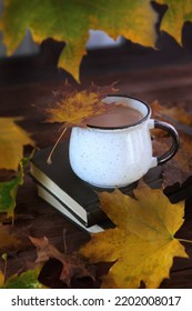 Coffee In A Cup And A Book On A Brown Background With Autumn Leaves. A Hot And Healthy Drink. Vertical Photo. Autumn Time Of The Year.