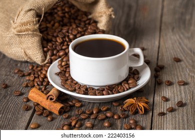 Coffee cup with cinnamon sticks and coffee bag on wooden table - Powered by Shutterstock