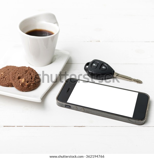 coffee cup with cookie,phone and car key on white\
wood table
