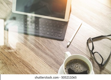 Coffee cup and Digital tablet dock smart keyboard,eyeglasses,stylus pen on wooden table,filter effect