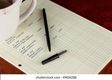 Coffee Cup With General Ledger Sheet Showing Journal Entries And Black Ballpoint Pen On Polished Wooden Table Top