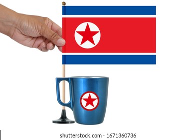 Coffee Cup And Hand Holding North Korean Flag On Wood Pole White Background