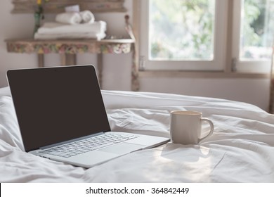 Coffee Cup And Laptop On The Bed In Morning Time, Focus On Cup