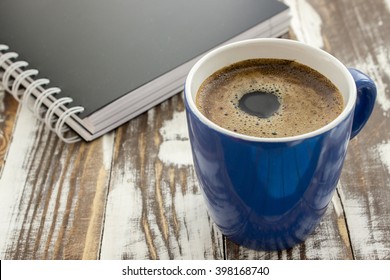 Coffee cup and notebook on the table.