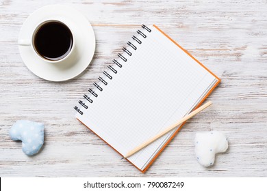 Coffee cup notepad pencil and two hearts on wooden surface