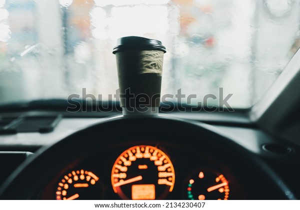 Coffee cup on car console during the rainy\
morning. Rush hour in the city\
concepts.\
