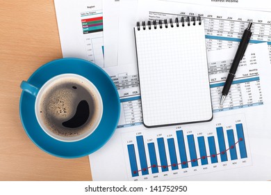 Coffee cup on contemporary workplace with financial papers and office supplies - Shutterstock ID 141752950