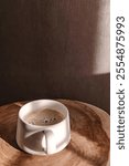 Coffee cup on a wooden table illuminated by warm sunlight, color of the year 2025 mocha mousse