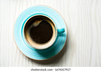 Coffee Cup On A Wooden Table From Above. Light Blue Coffee Cup On Wooden Background. Fresh Coffee With Milk In Blue Coffee Mug And Saucer On Wooden Background 