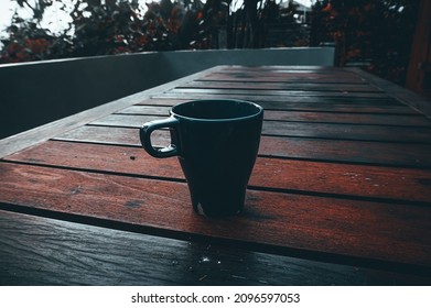 Coffee Cup On Wooden Table With Blurry Backyard Background. Dark Tone Colour.