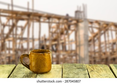 Coffee Cup On Wooden Table With Construction Site Background