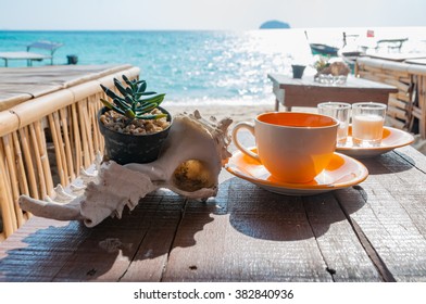 Coffee cup on the wooden table in front of the beach in a beautiful morning sunlight in Lipe island, Satun, Thailand
