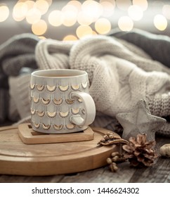 Coffee Cup Over Christmas Lights Bokeh In Home On Wooden Table With Sweater On A Background And Decorations. Winter Mood, Holiday Decoration, Magic Christmas.