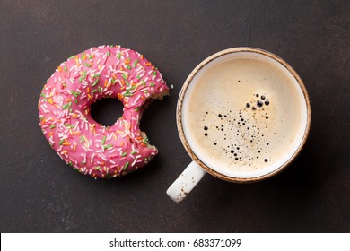 Coffee Cup And Pink Donut On Stone Table. Top View