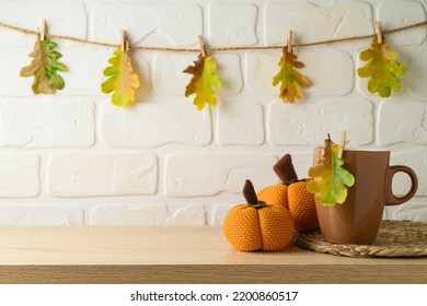 Coffee Cup And Pumpkin Decoration On Wooden Shelf Over Brick Wall Background With Autumn Leaf Garland. Thanksgiving Holiday Greeting Card