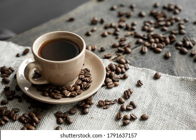 Coffee cup with roasted coffee beans on wooden table background. Mug of black coffe with scattered coffee beans on a wooden table. Fresh coffee beans. - Powered by Shutterstock