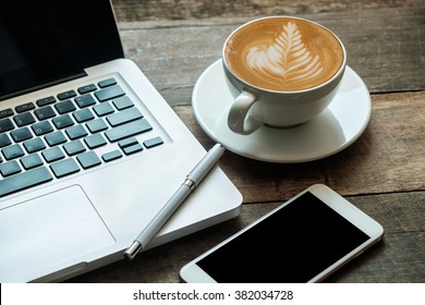 Coffee cup smart phone and laptop on wood table. View from above - Powered by Shutterstock