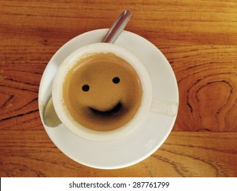 Coffee Cup With Smiley Face Over Wooden Surface