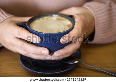 Coffee Cup. Soft Focus. Lady's Hands Holding Cappuccino. Unrecognized Woman Wearing Warm Knitted Sweater with Blue Mug of Latte. Close Up. Cropped Shot. Unrecognized Female Person. Hugge Winter Mood