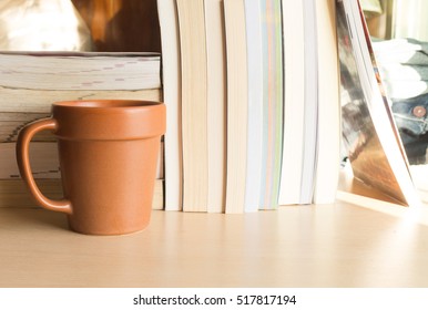 coffee cup and stack of book on wood table