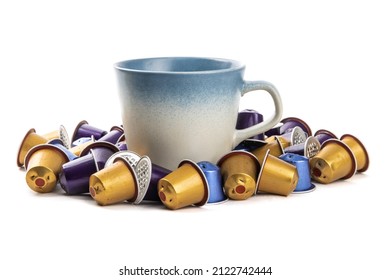 A coffee cup surrounded by a pile of colorful used espresso coffee maker pods isolated on white