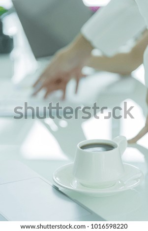 A coffee cup with white plate on the office desk.
