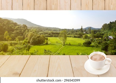 Coffee cup with wood texture on blur green rice field and mountain.