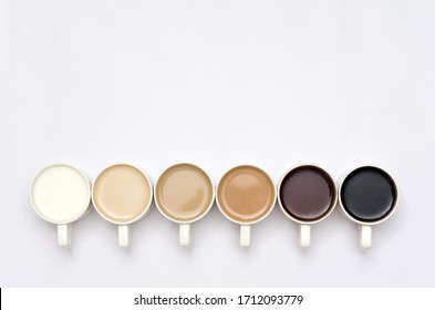 Coffee cups arranged in creative way creating gradient colour palette effect white background