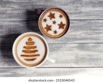 Coffee cups with Christmas tree and star symbols on frothy surface flat lay on grey painted wood plank background. Holidays food art theme for Merry Christmas and Happy New Year (top view, copy space) - Powered by Shutterstock