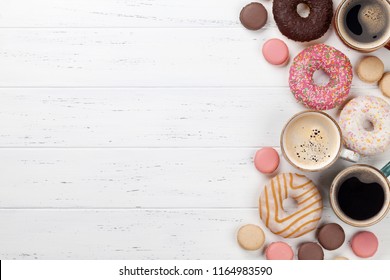 Coffee cups, donuts and macaroons on white wooden table. Top view with space for your text - Powered by Shutterstock