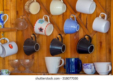 Coffee cups hanging on hooks in front of wood wall  - Powered by Shutterstock