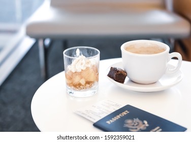 Coffee, Dessert And Passport On White Table In Business Lounge Zone In Airport. 